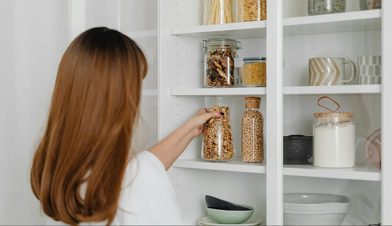 woman putting away jar on shelf 